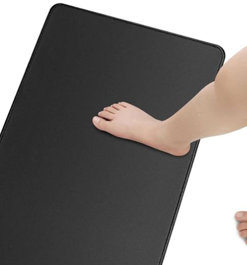 Le tapis de pieds noir, un pied nu posé dessus